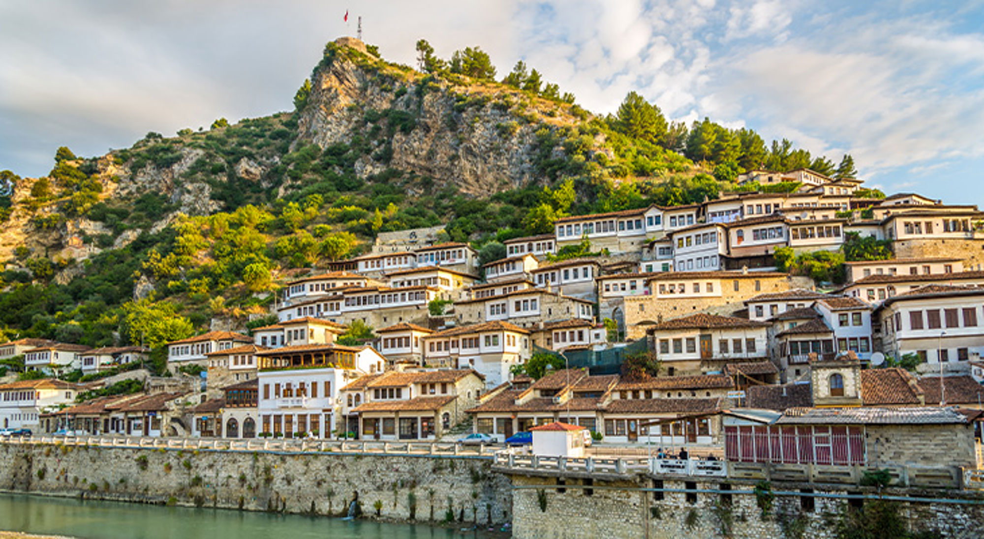 Berat Huizen tegen een groene berghelling langs de rivier in Berat, Albanië.