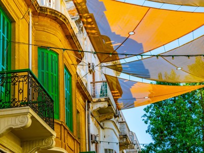 Historische gevels met groene luiken en balkons onder schaduwdoeken in een straat op Cyprus.
