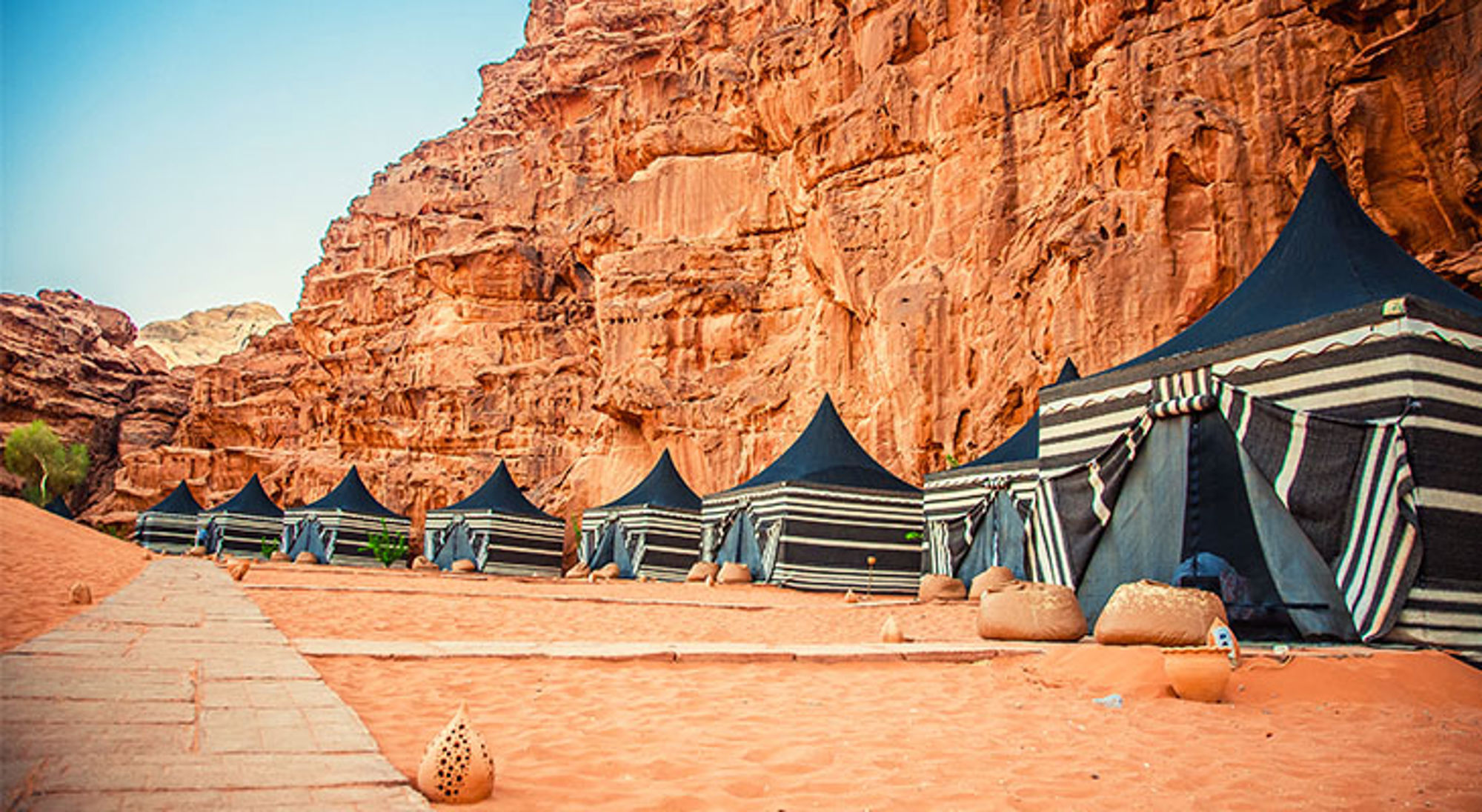 Rijtje bedoeïenententen in de Wadi Rum-woestijn, met rode rotswanden op de achtergrond.
