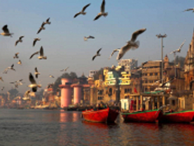Rode boten op de Ganges bij de ghats van Varanasi, met vliegende meeuwen en tempels op de oever.