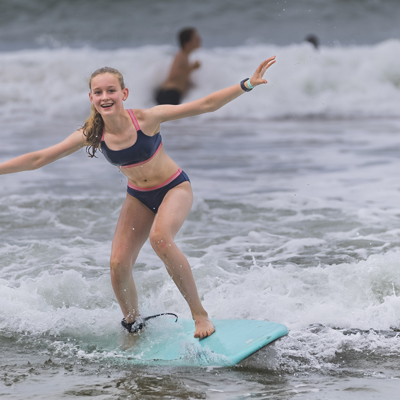 Kind surft op een golf aan het strand tijdens een familiereis in Costa Rica.