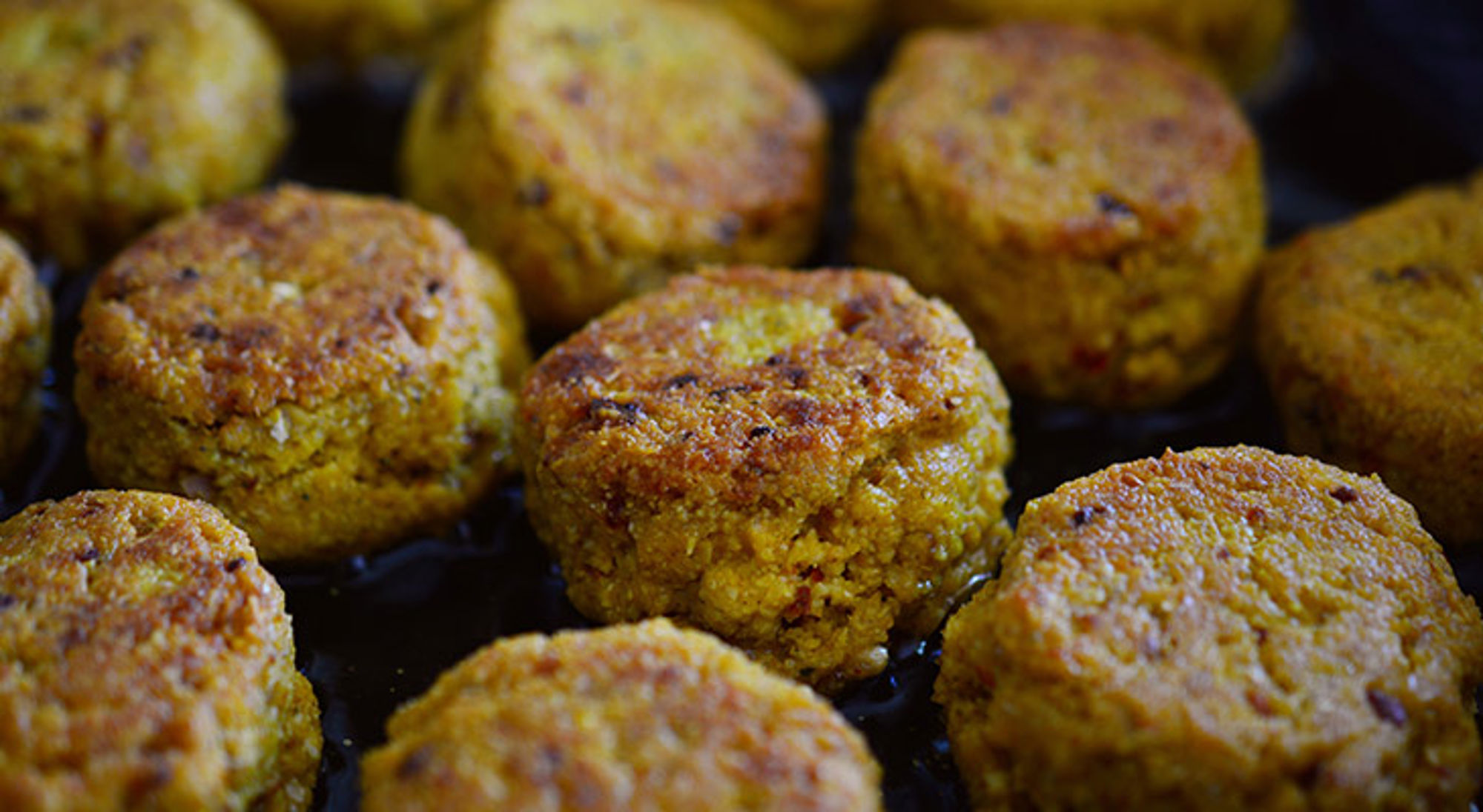 Goudbruin gebakken falafelballetjes in een pan.