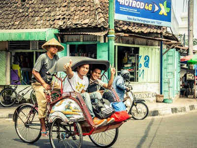 Becak met twee passagiers in een straat op Java tijdens de route Java en Bali.