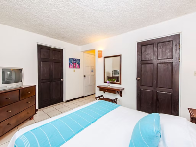 Hotelkamer in Pueblo Dorado met tweepersoonsbed, tv, spiegel en houten kastdeuren.