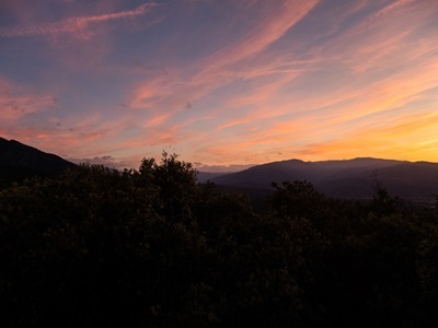 Zonsondergang boven de bergketens van de Pyreneeën tijdens Route Canigou, met silhouetten van bos in de voorgrond.