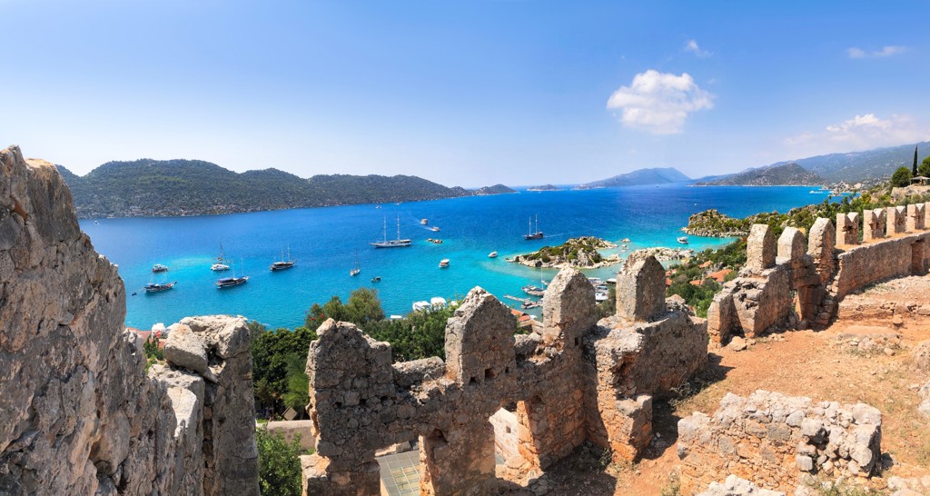 Uitzicht op de Turquoise Kust in Turkije met baai vol zeilboten, gezien vanaf een oude vestingmuur.