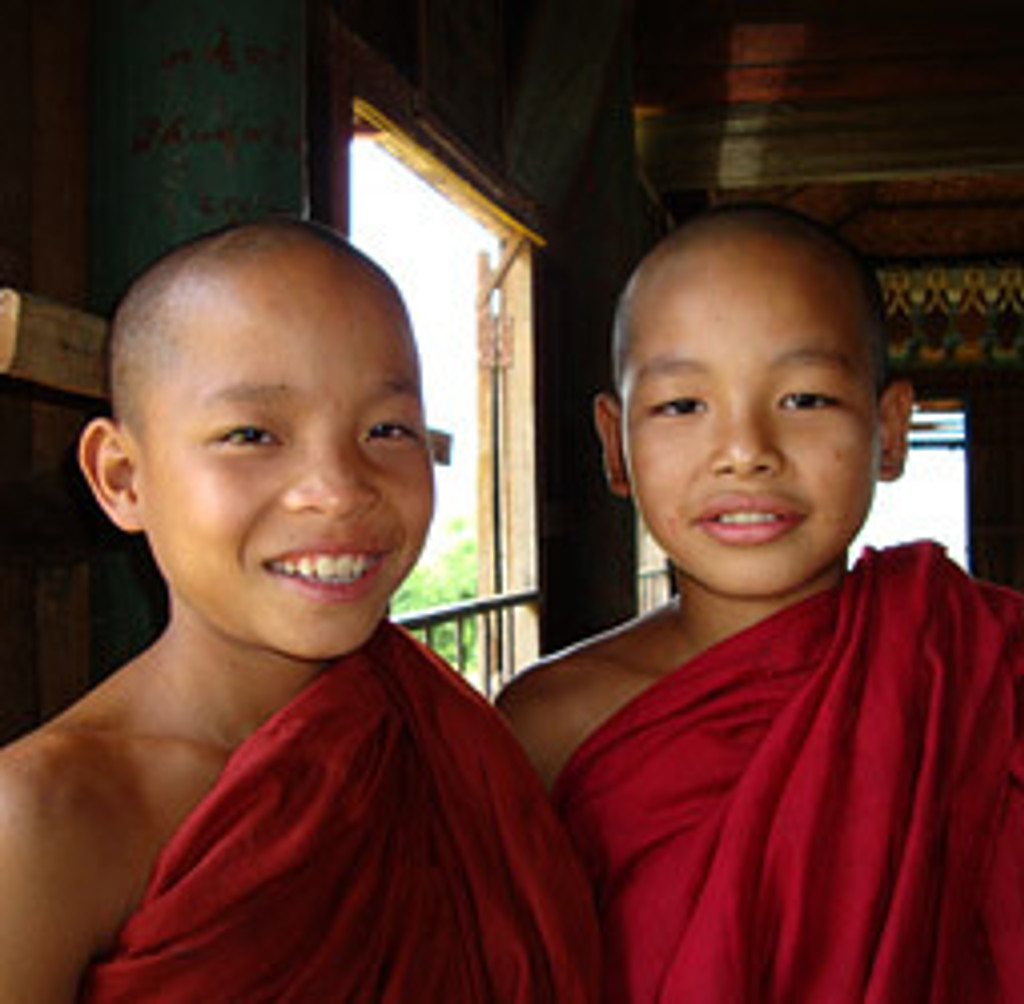 Twee jonge boeddhistische monniken in rode gewaden in Myanmar tijdens een familiereis.