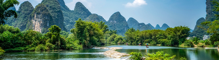 Karstbergen en groene rivier met bamboe en bootjes bij Yangshuo, China.