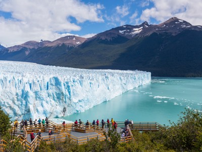 Uitzicht op de Perito Moreno-gletsjer in Patagonië vanaf een houten uitkijkplatform met bezoekers.