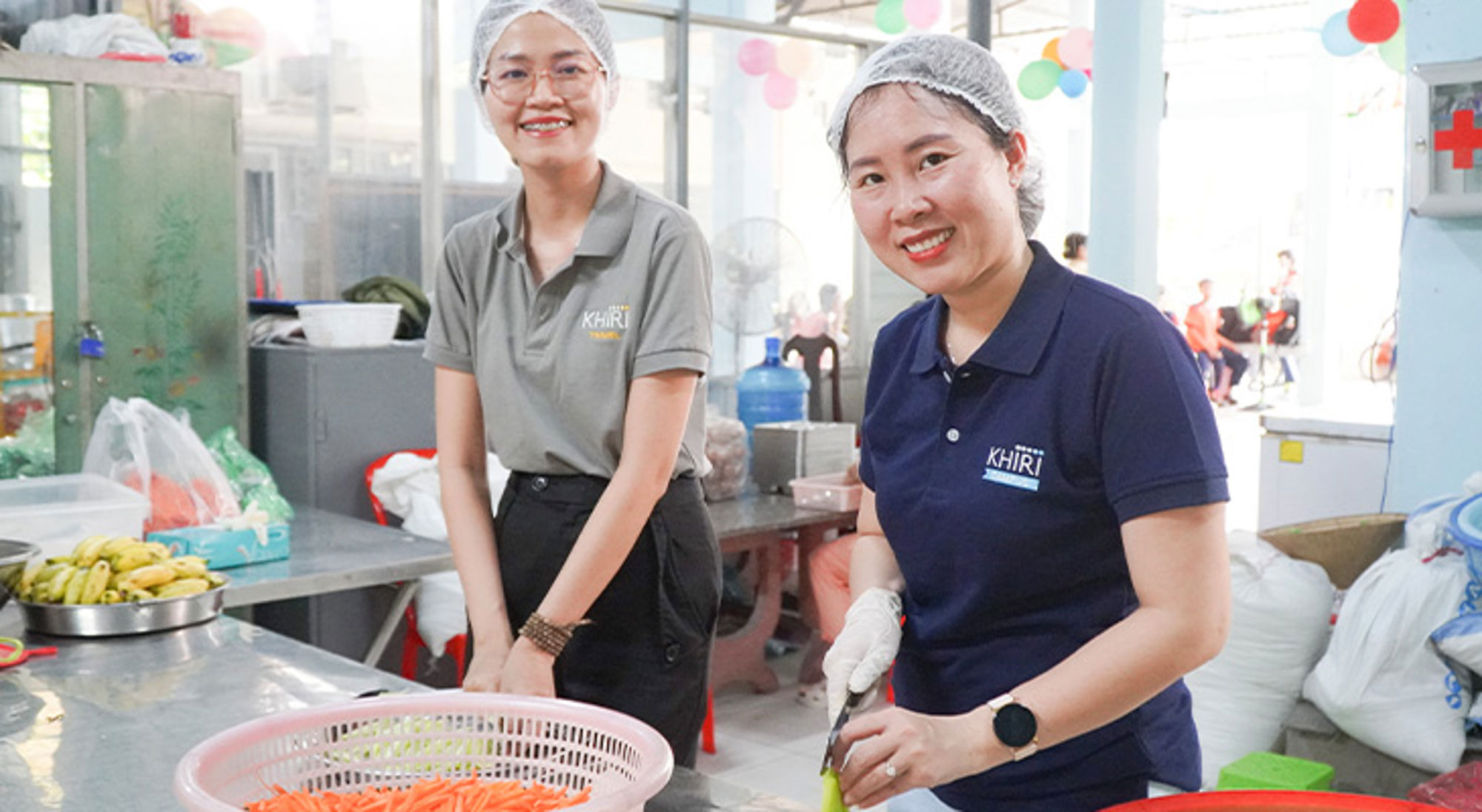 Medewerkers van Khiri Travel bereiden groenten in een keuken tijdens een sociaal project.