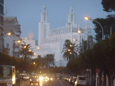 Verlichte boulevard in Casablanca met de witte Hassan II-moskee op de achtergrond.