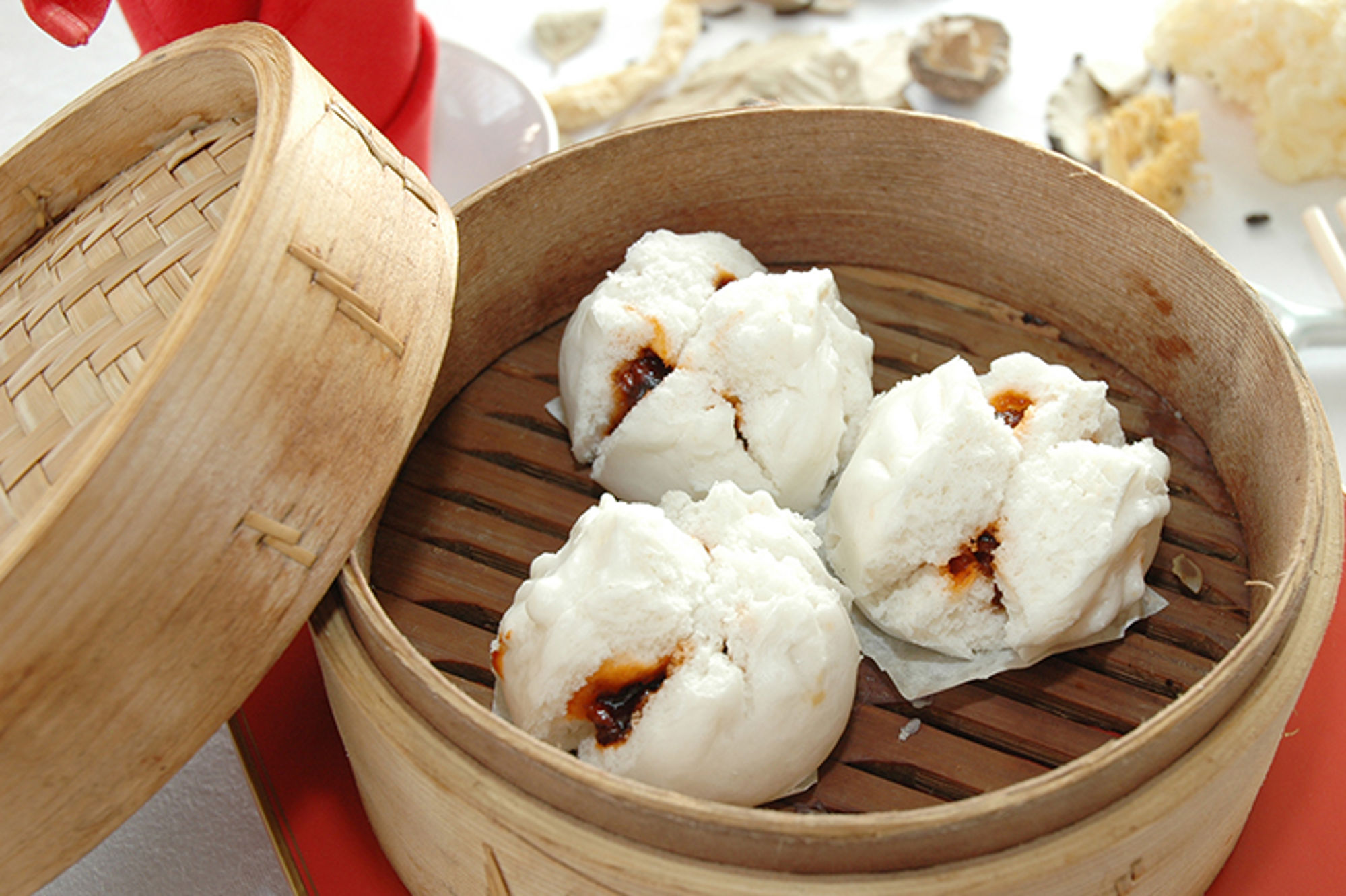 Gestoomde Chinese bao buns met zoete vulling in een bamboe stoommandje.
