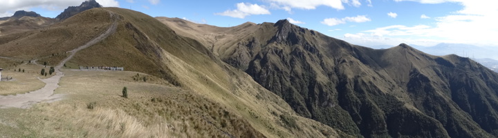 Uitzicht over bergkam in de Andes bij Quito, Ecuador, met wandelpad en ruige bergtoppen onder blauwe lucht.