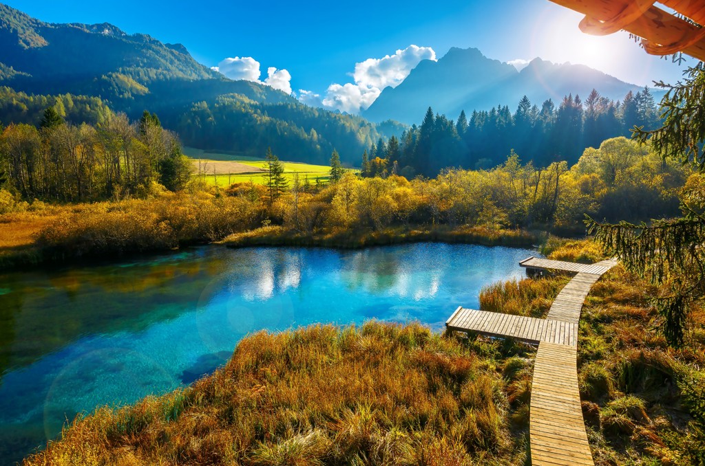 Turquoise bergmeer met houten wandelpad, omringd door bossen en bergen in Slovenië, Centraal Europa.