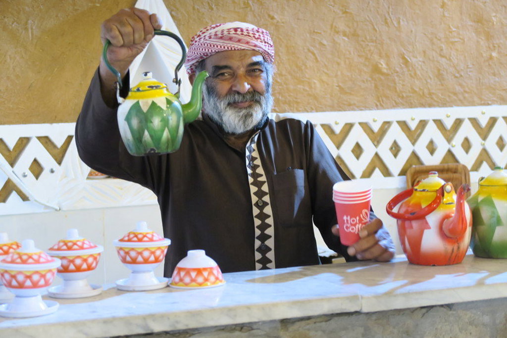 Saoedische man schenkt koffie uit traditionele theepot tijdens groepsrondreis Saoedi-Arabië.