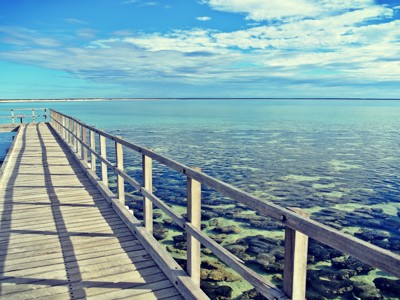 Houten pier over helderblauw water aan de kust van West-Australië tijdens de 25-daagse route.