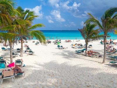 Wit zandstrand met palmbomen, ligbedden en turkooisblauwe zee tijdens Route Mexico.
