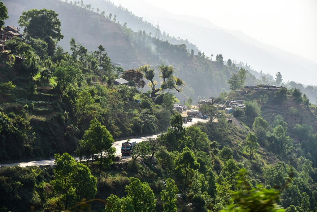 Groene heuvels met slingerende weg en dorp in de bergen van Nepal tijdens een 22-35ers reis.