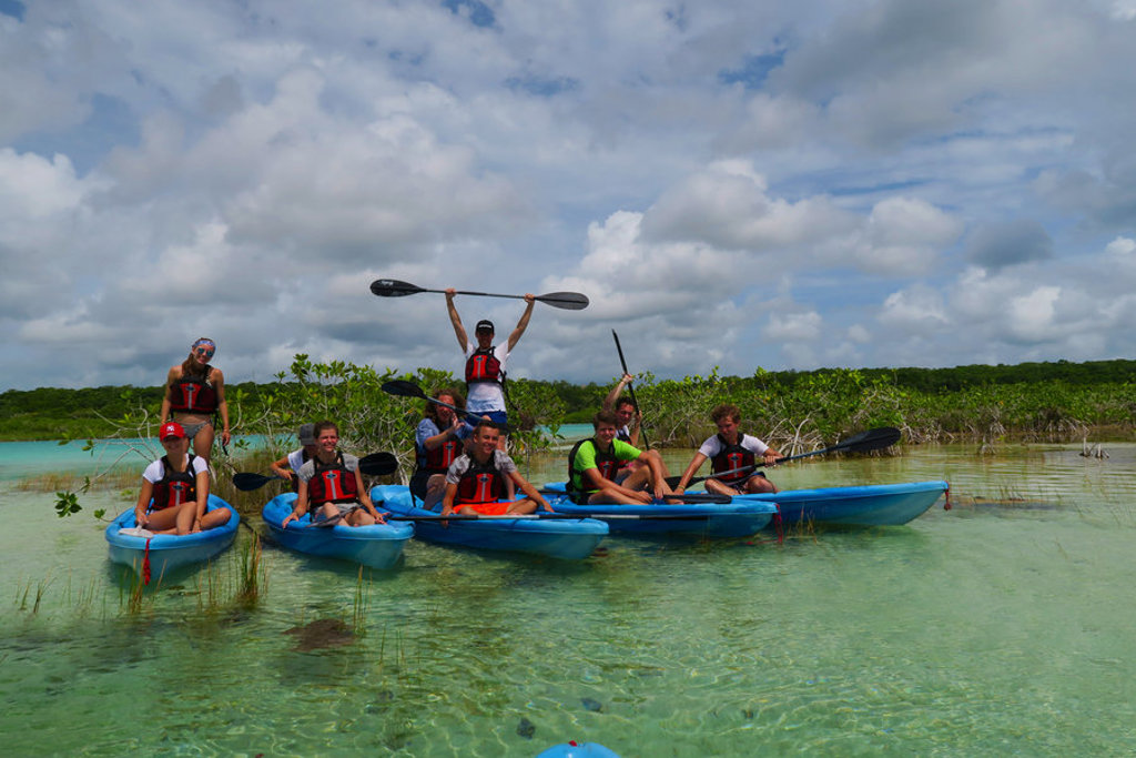 Familie kajakt in helderblauwe lagune tijdens familiereis Mexico hoogtepunten.