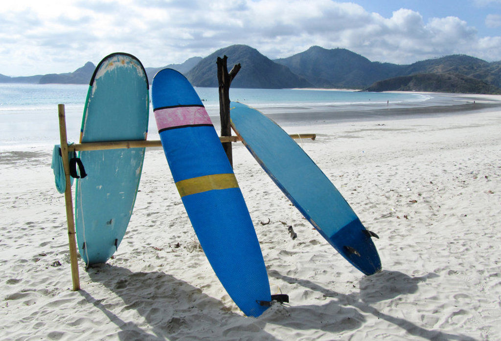 Surfboards op het strand van Bali met zee en bergen op de achtergrond.