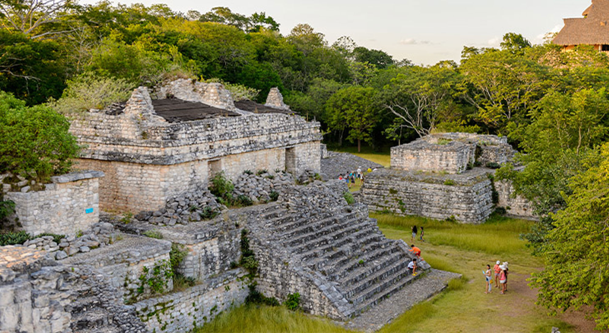 Ek' Balam Maya-ruïnes met stenen tempels en trappen, omringd door jungle en bezoekers.