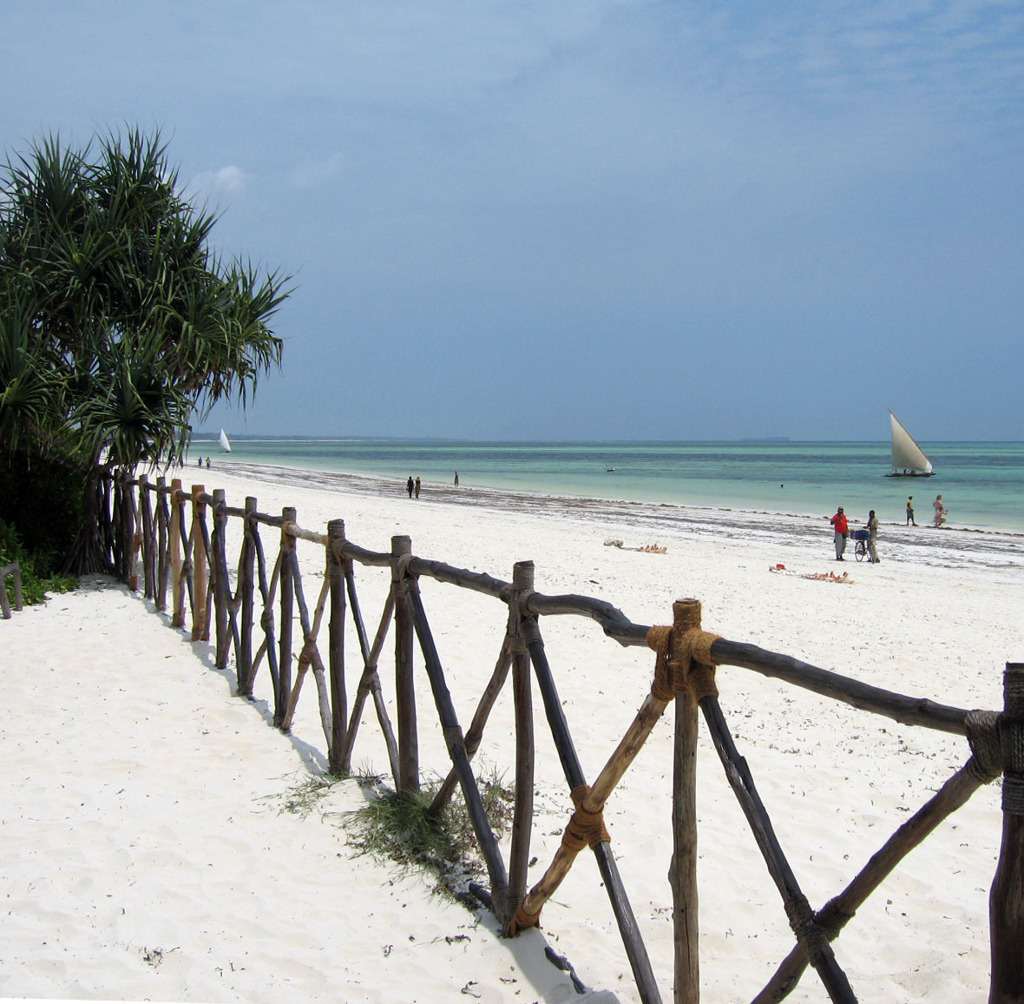 Wit zandstrand met turquoise zee en zeilboot bij Zanzibar, onderdeel van groepsrondreis Kenia, Tanzania en Zanzibar.