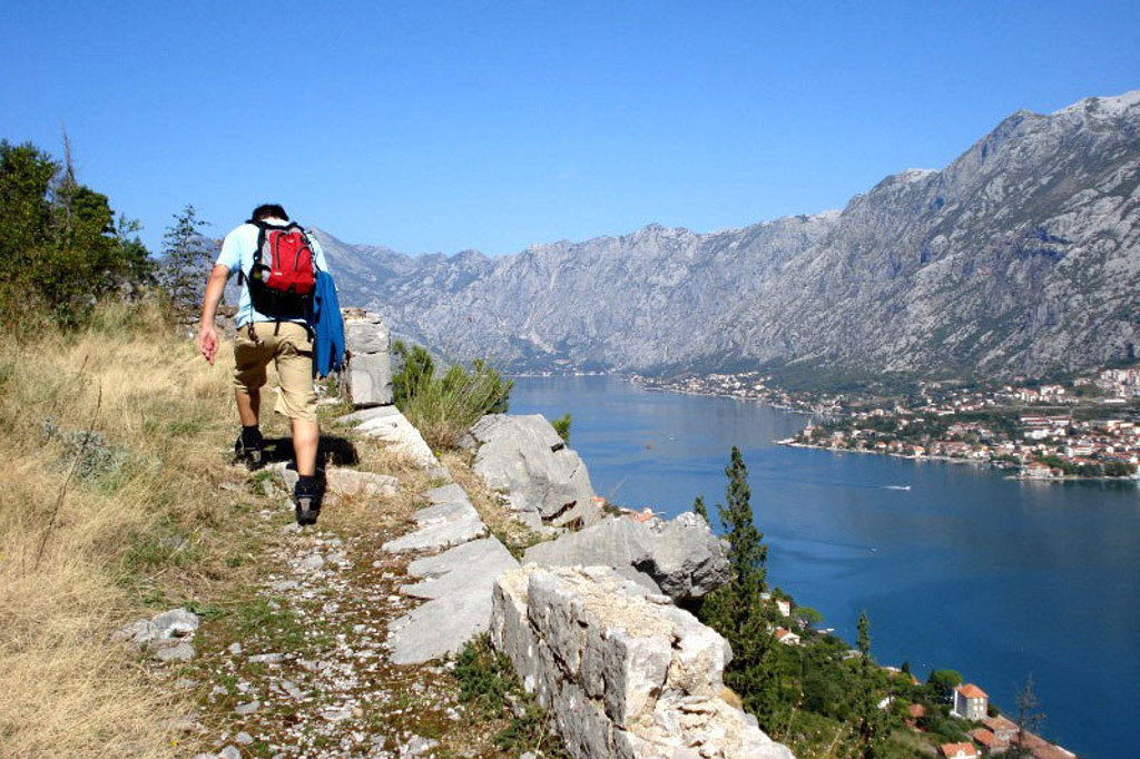 Wandelaar met rugzak op bergpad met uitzicht op de Baai van Kotor, tijdens groepsrondreis Balkan.