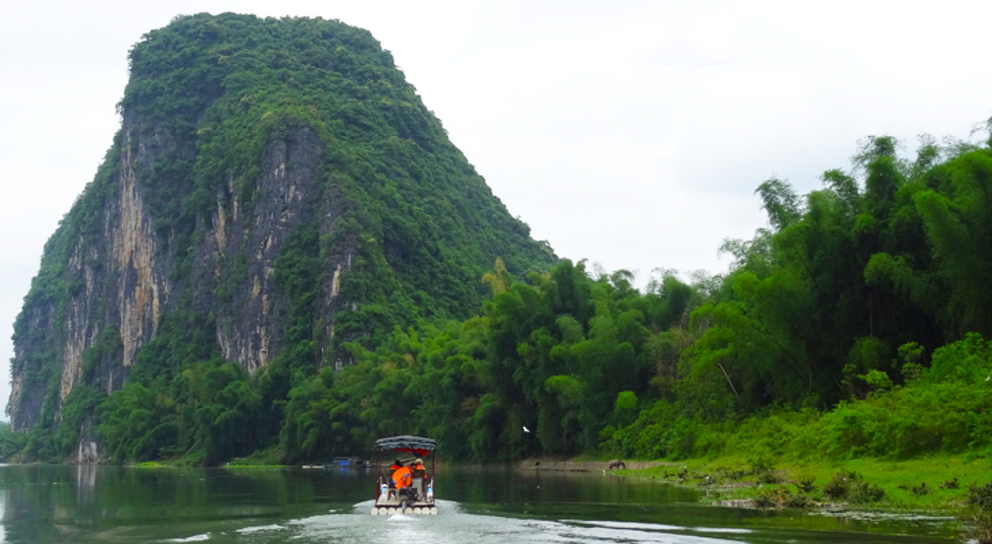 Bootje in Yangshuo National Park, China Bamboevlot op de rivier met karstberg en groene jungle op de achtergrond.
