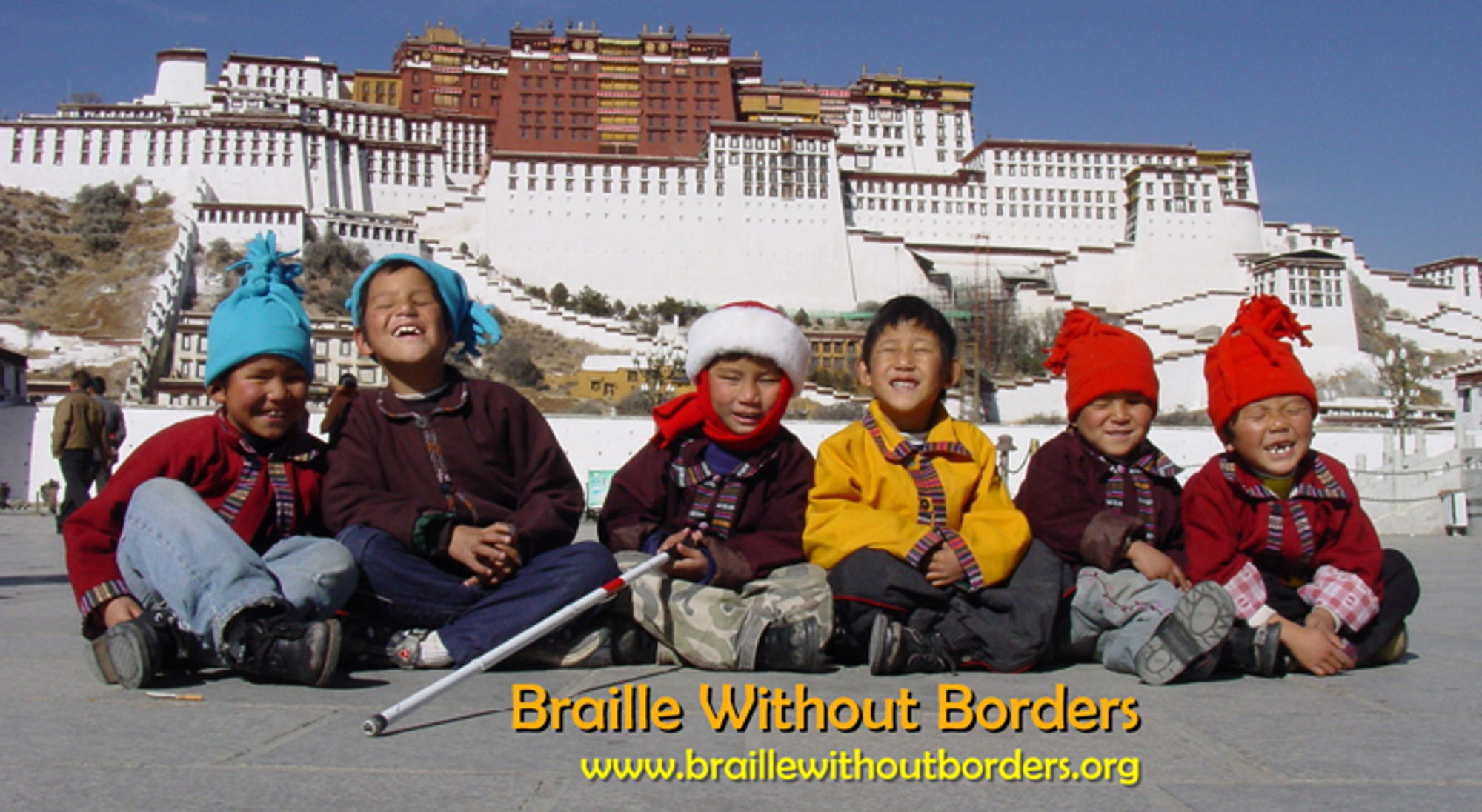 Kinderen in winterkleding zitten voor het Potala-paleis in Lhasa, Tibet.