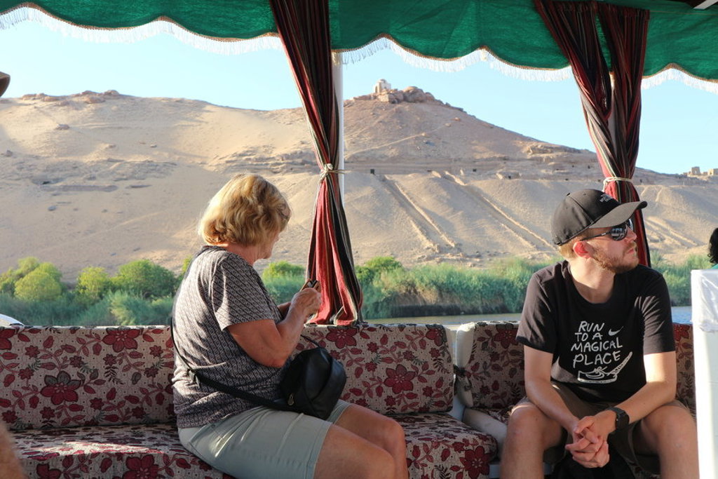 Reizigers op een felucca op de Nijl met uitzicht op woestijnheuvels tijdens de groepsrondreis Egypte Hoogtepunten.