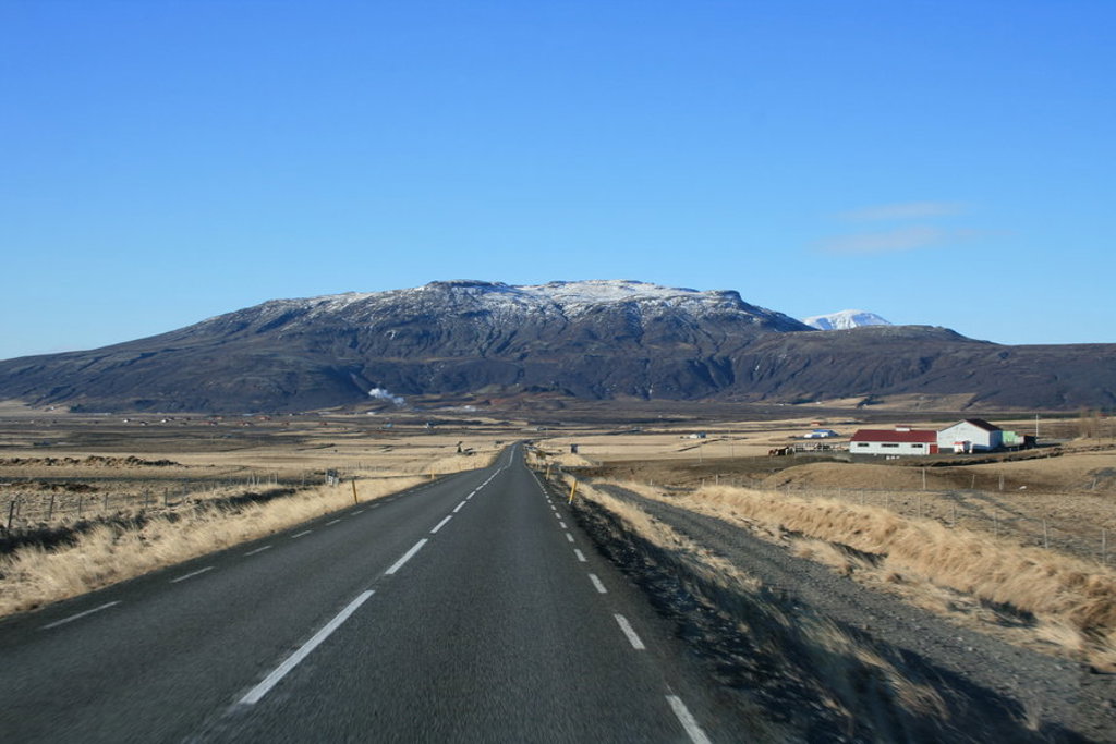 Lange weg door het IJslandse landschap richting besneeuwde bergen tijdens groepsrondreis IJsland kamperen.