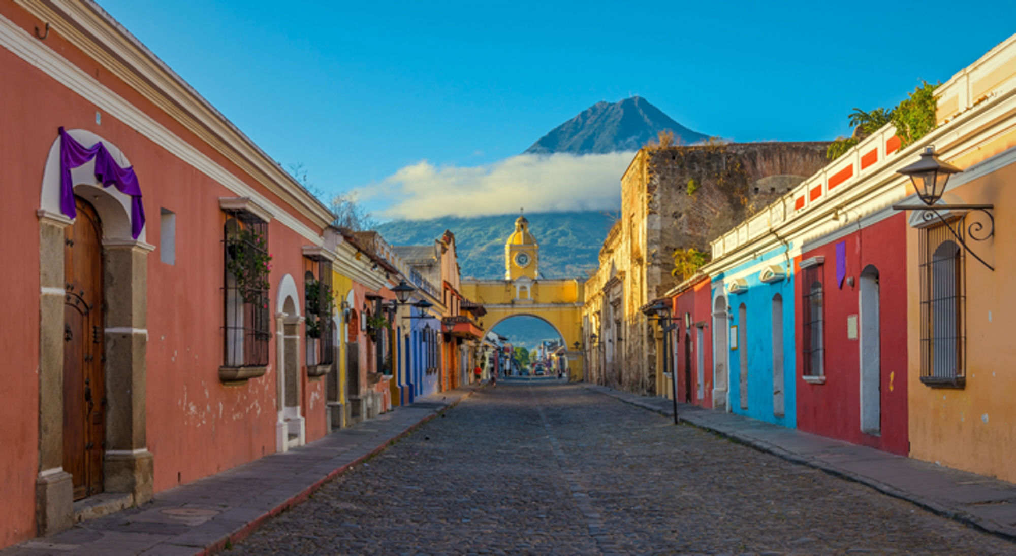 Kleurrijk Antiqua, Guatemala Kleurrijke straat in Antigua Guatemala met de Santa Catalina-boog en de vulkaan Agua op de achtergrond.
