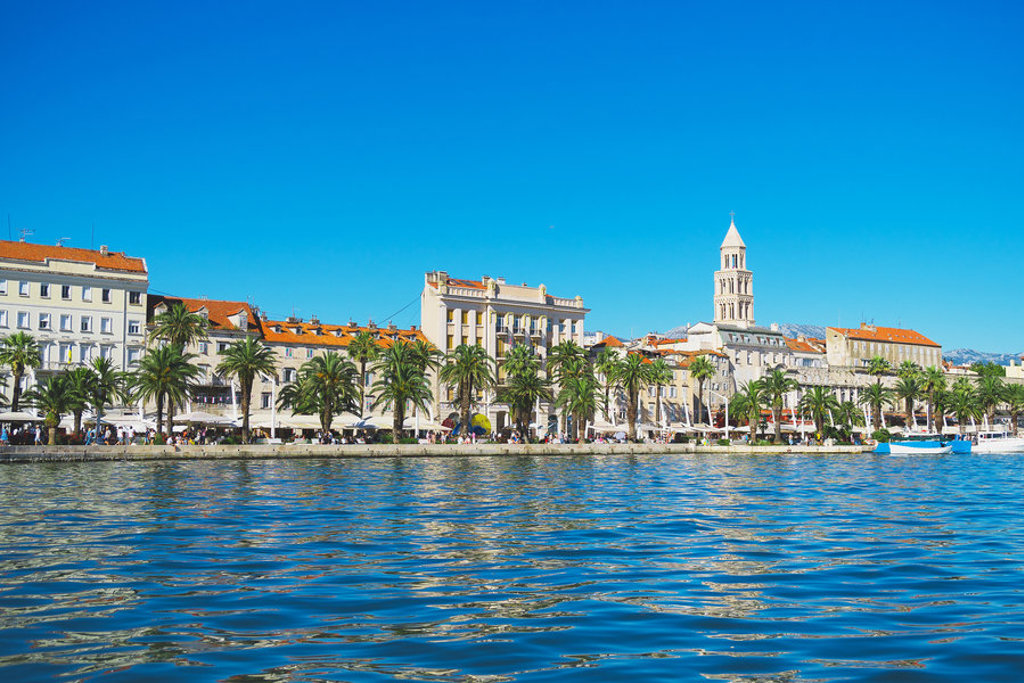 Boulevard en haven van Split in Kroatië met palmbomen en de klokkentoren van de kathedraal.