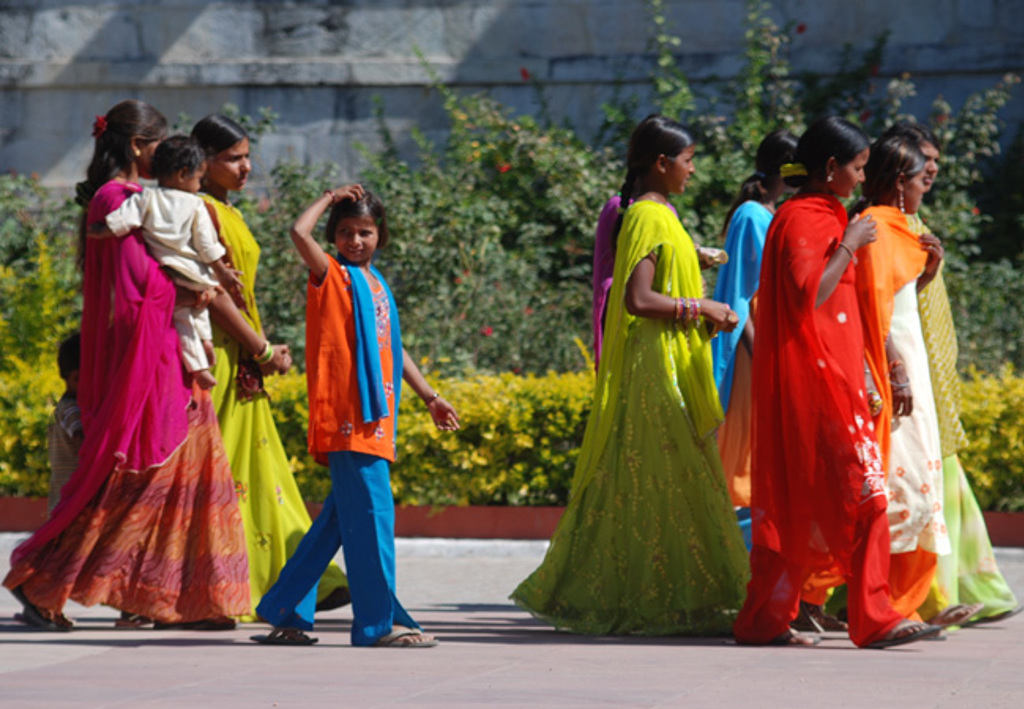 Vrouwen en kinderen in kleurrijke kleding lopen over straat in Gujarat, India.