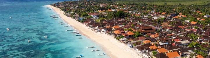 het strand en de kustplaats op Nusa Lembongan met turquoise zee en bootjes.