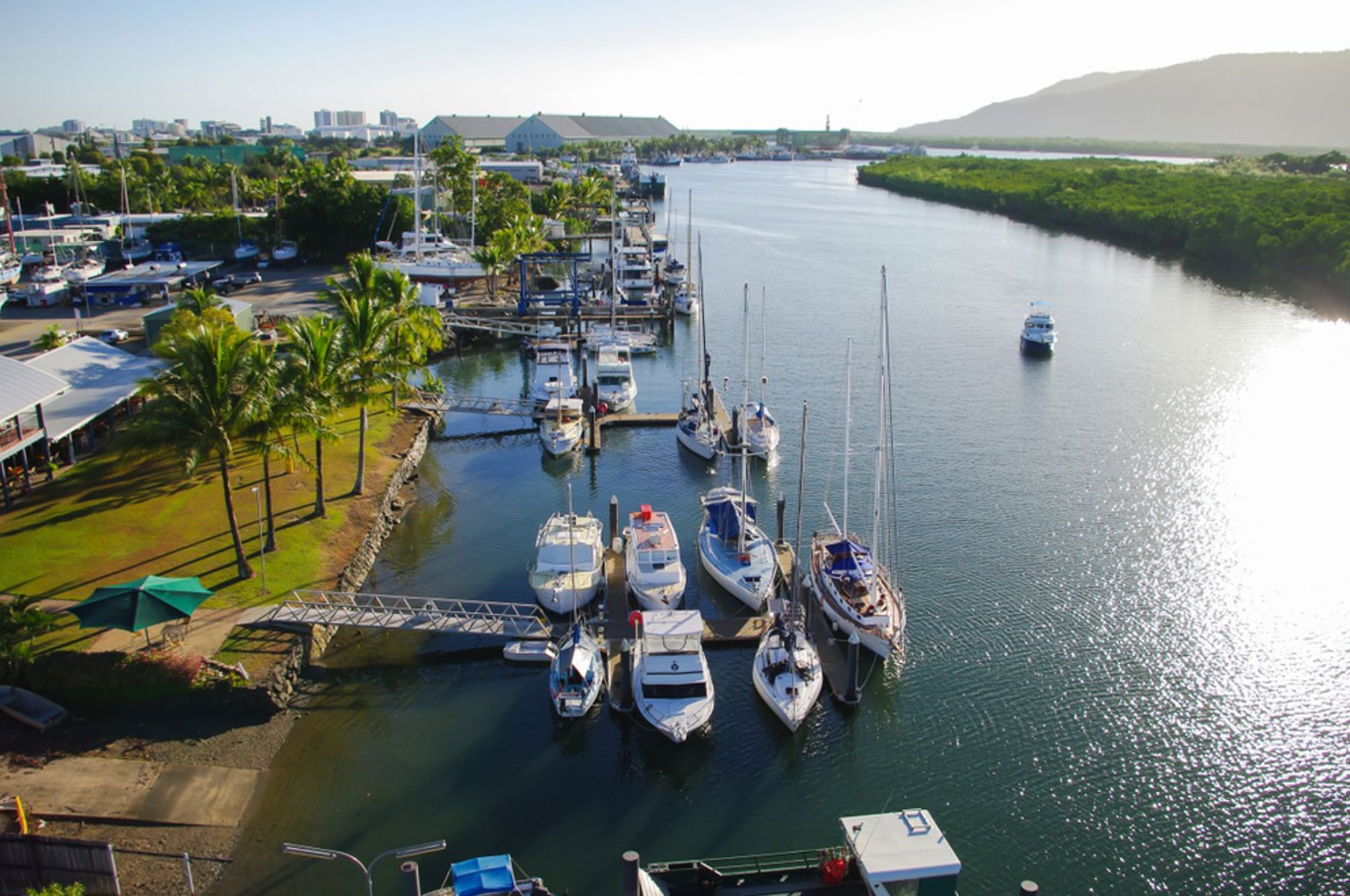 Jachthaven met zeilboten en palmbomen aan een rivier in Australië.