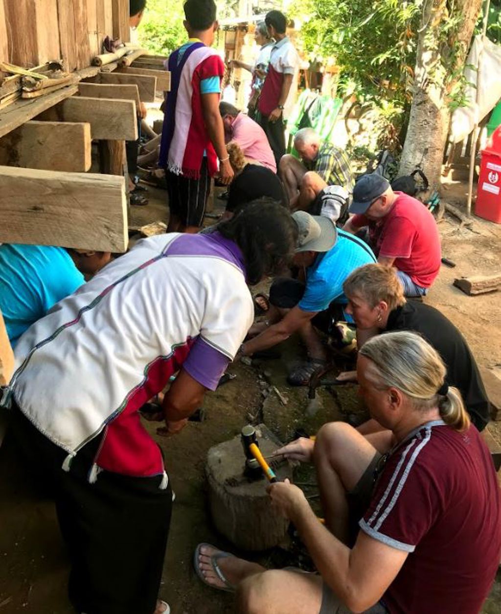 Groepsrondreis Thailand: reizigers helpen mee met een lokaal project en werken met gereedschap in de buitenlucht.