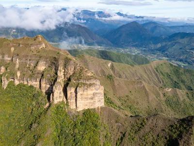 Uitzicht over de Quilotoa Loop met groene Andesbergen, rotsformaties en wolken boven de vallei in Ecuador.