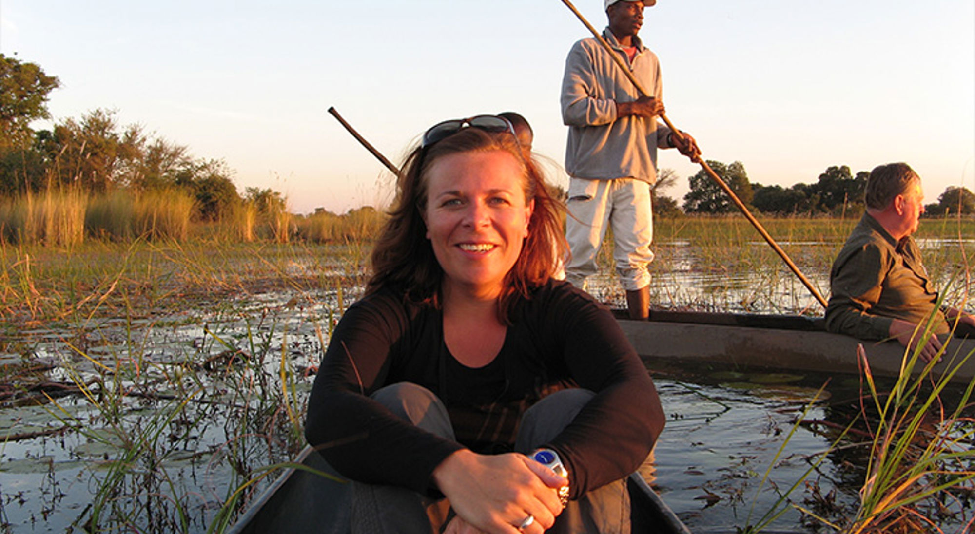 Vrouw in kano tijdens mokorotocht door de Okavango Delta bij zonsondergang.