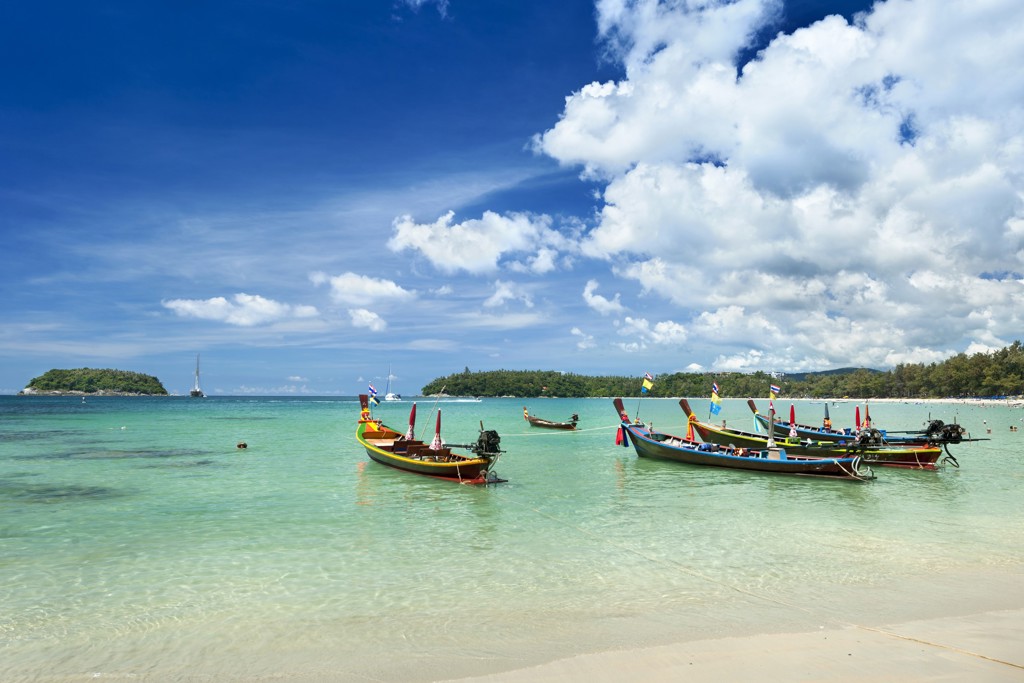 Longtailboten in helderblauw water bij een wit zandstrand in Thailand, tijdens de rondreis Noord en Zuid Hoogtepunten.