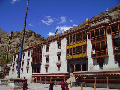 Kleurrijk boeddhistisch klooster in Ladakh tegen een rotswand en helderblauwe lucht.