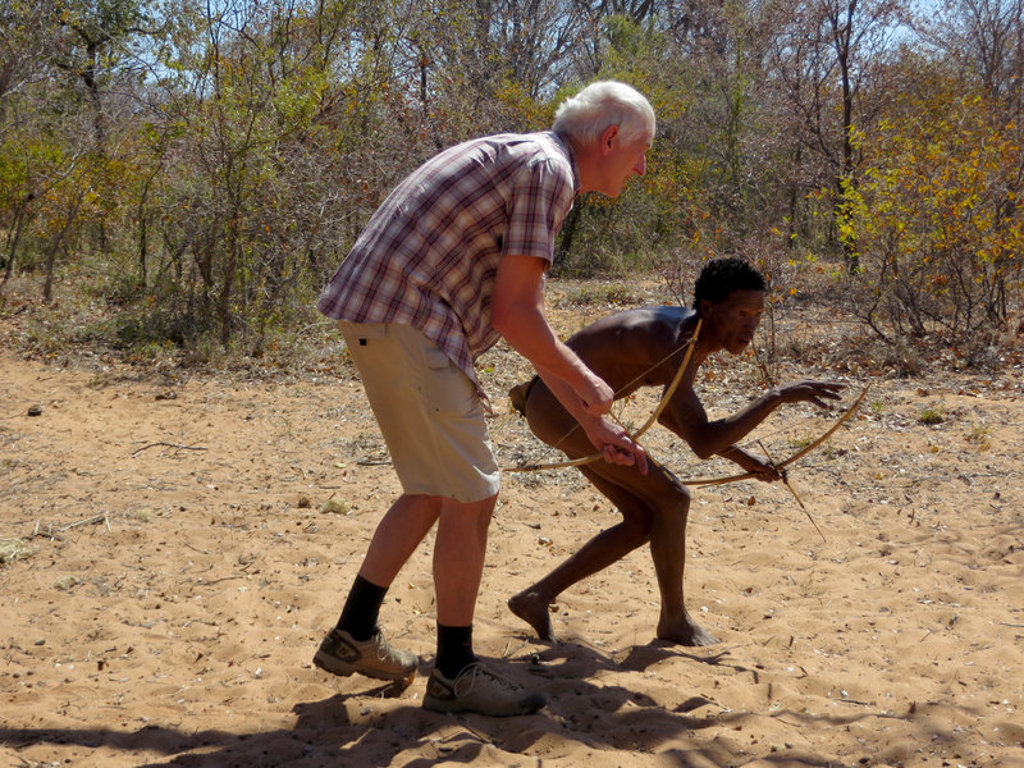 Reiziger oefent boogschieten met lokale gids tijdens groepsrondreis Namibië.