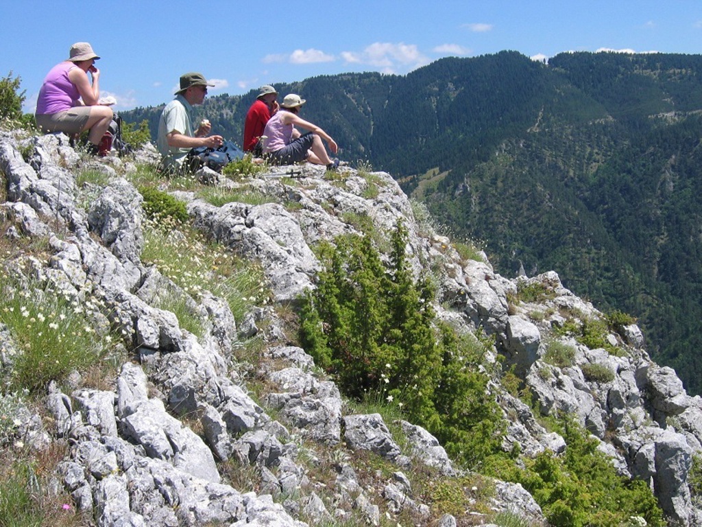 Wandelaars pauzeren op een rotsige bergkam met uitzicht op de Bulgaarse Balkan tijdens een wandelvakantie in Bulgarije.