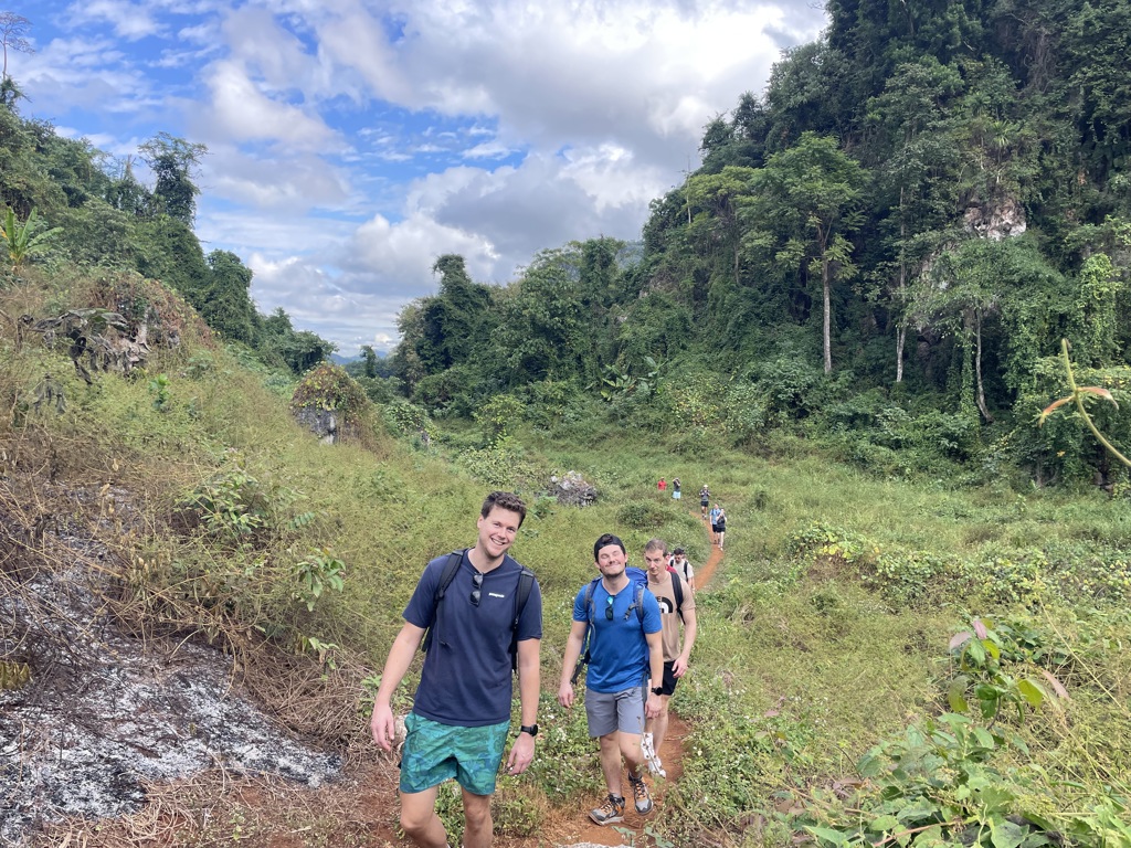 22-35ers wandelen over een smal pad door groene jungle tijdens de reis Thailand, Laos en Cambodja.