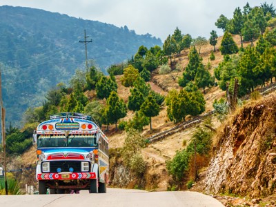 Felgekleurde chicken bus op een bergweg in Guatemala, route richting Copán.