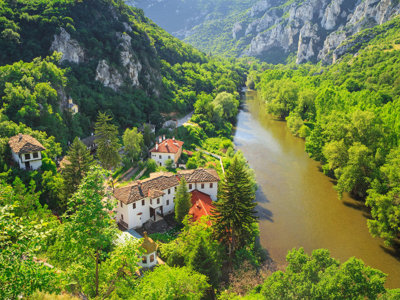 Groene rivierkloof met klooster en huizen langs de rivier, route van de Oriënt Express naar Istanbul.