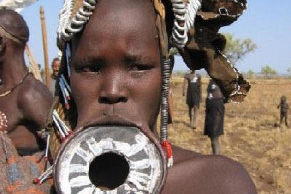 Portret van een man met traditionele lipplaat en hoofdtooi in Ethiopië tijdens een groepsrondreis.