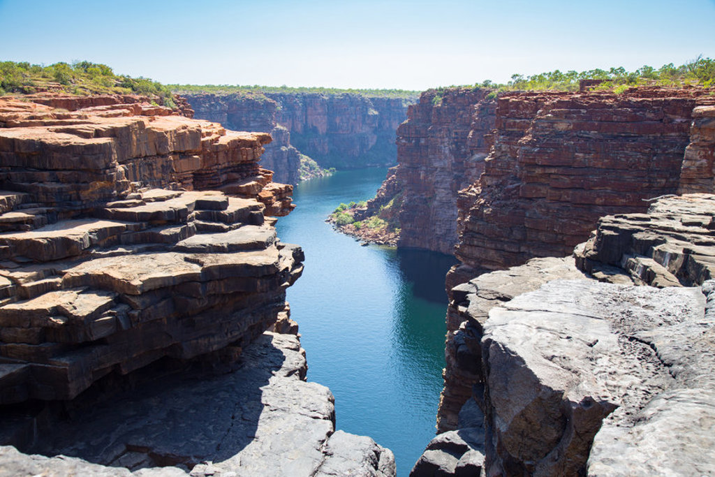 Uitzicht over een diepe kloof met rivier tussen rotswanden in West-Australië tijdens een groepsrondreis.