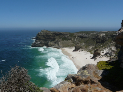 Uitzicht op Kaap de Goede Hoop met rotskliffen, wit zandstrand en golven langs de kust van Zuid-Afrika.