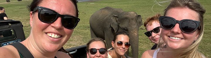 22-35ers reis in Sri Lanka: groep reizigers maakt selfie tijdens safari met olifant op de achtergrond.